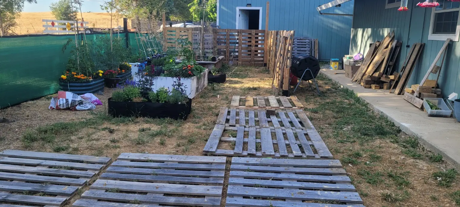 Raised garden beds beside pallets laid out for construction