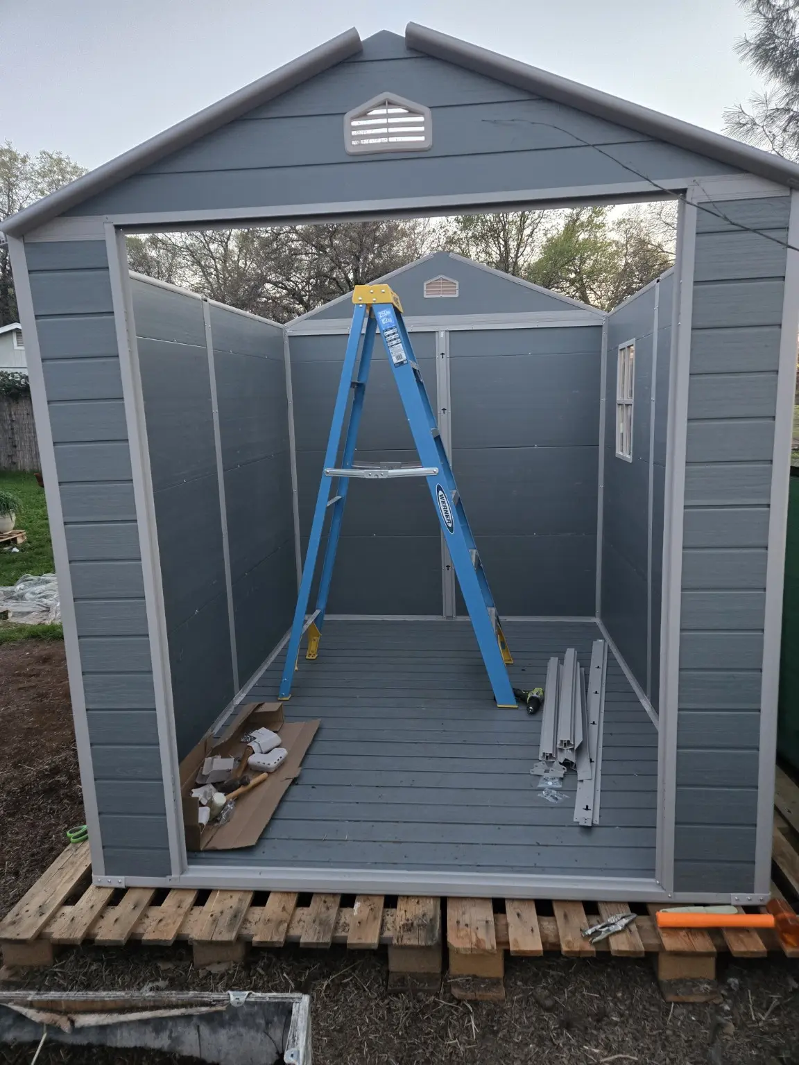 The partially assembled resin shed with a ladder and construction pieces inside